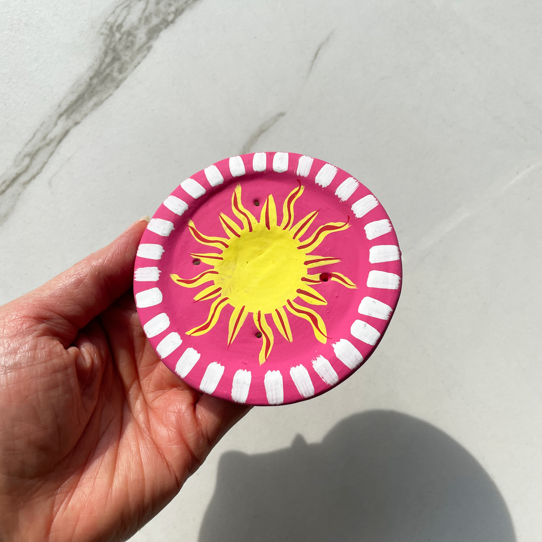4 inch round terracotta incense burner for incense cones and sticks hot pink and white with yellow sun design in center bliss shop chicago