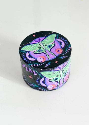2.5 inch diameter purple aluminum 4 piece grinder with black background and green moth with celestial and floral design bliss shop chicago