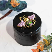 canna style 2.5 inch diameter black aluminum 4 piece grinder with  beetle encrusted in lavender gems & pearls on top lid bliss shop chicago