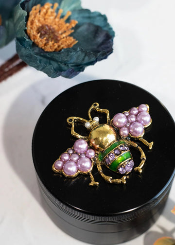 canna style 2.5 inch diameter black aluminum 4 piece grinder with  beetle encrusted in lavender gems & pearls on top lid bliss shop chicago