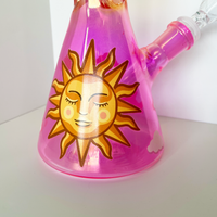 10 inch beaker bong with a bright pink base that transitions to yellow gold at top with large celestial sun, butterflies and cloud decals bliss shop chicago